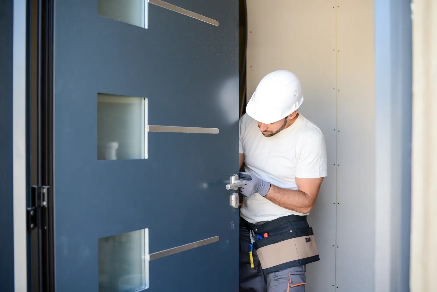 Hübscher junger Mann, der eine Tür auf einer neuen Hausbaustelle installiert